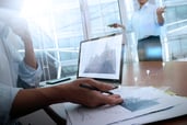 business documents on office table with smart phone and laptop computer and graph business with social network diagram and two colleagues discussing data in the background